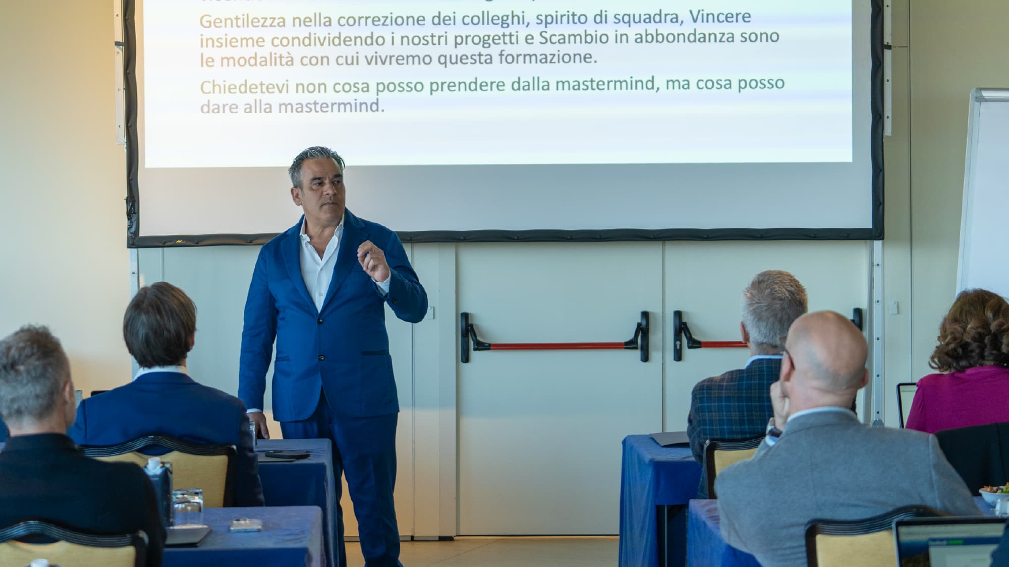 Aula di un corso Titolare Top: pochi titolari ai tavoli, il formatore in piedi davanti a loro